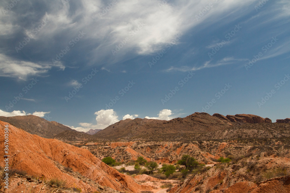 Geology. Arid desert landscape. Panorama view of the red and orange sandstone, rocks and hills under a blue sky. 