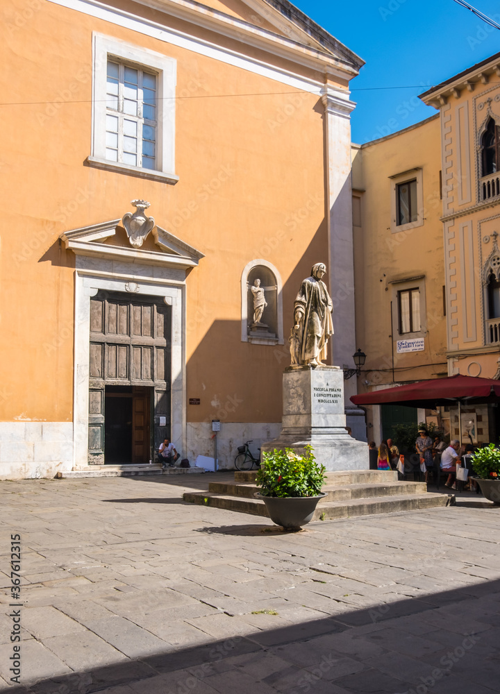 Pisa, Italy - August 14, 2019: Monument to Nicola Pisano and Santa Maria del Carmine church in Pisa, Tuscany, Italy