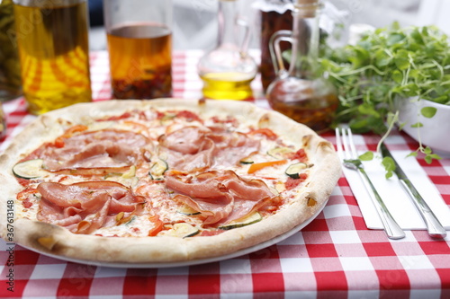 Pizza with ham and zucchini and mozzarella cheese. Italian cuisine. Traditional Italian pizza. Suggestion to serve a dish. Food background.