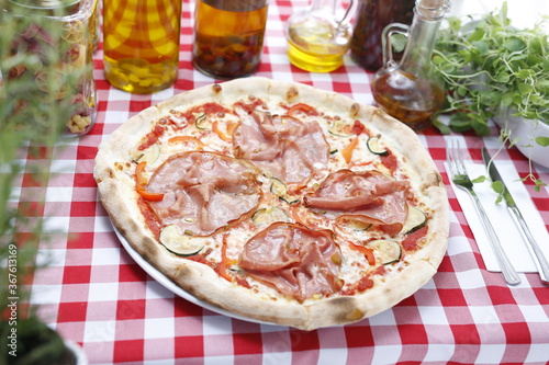 Pizza with ham and zucchini and mozzarella cheese. Italian cuisine. Traditional Italian pizza. Suggestion to serve a dish. Food background.