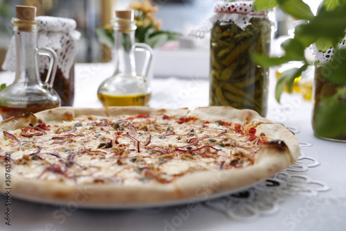 Pizza with tuna, onion, capers, and mozzarella cheese. Italian cuisine. Traditional Italian pizza. Suggestion to serve a dish. Food background.