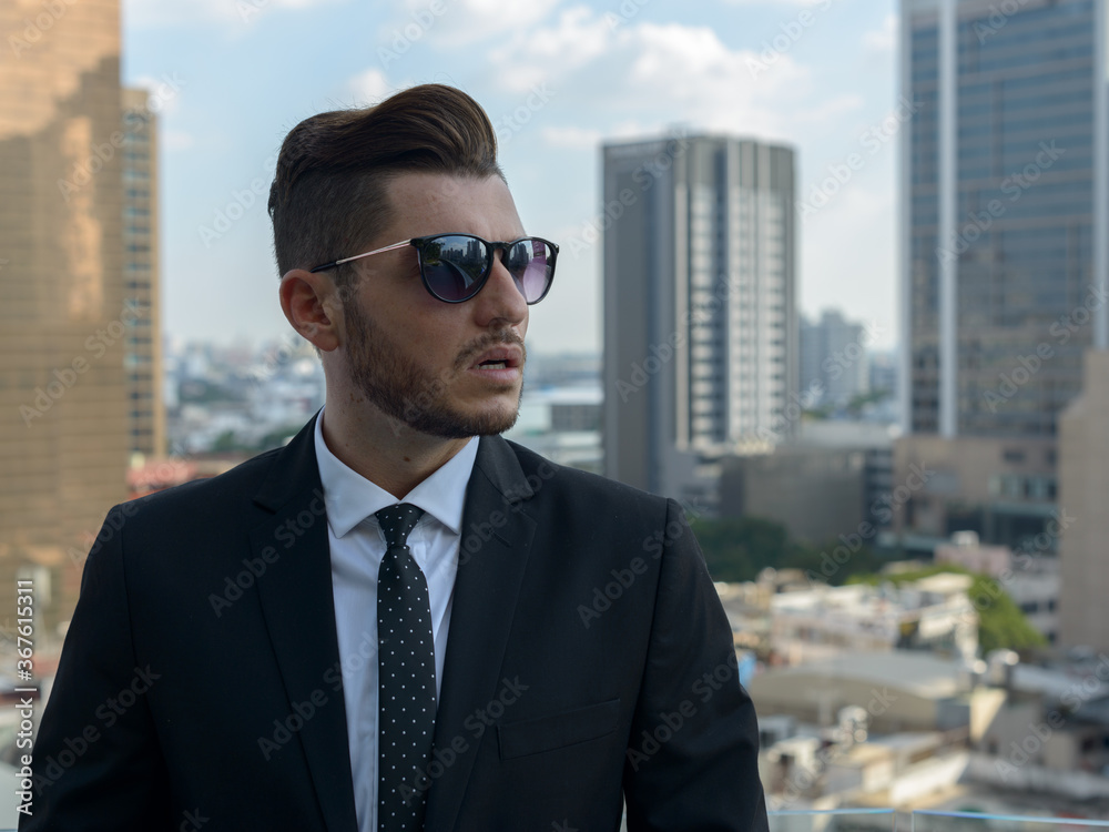 Handsome bearded Hispanic businessman against view of the city Handsome bearded Hispanic businessman against view of the city