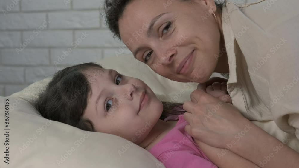 With mother before bedtime. Portrait of mother and daughter in the morning in bed.