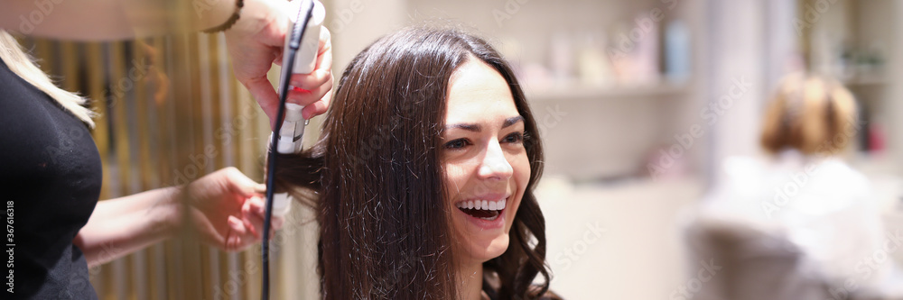 Fototapeta premium Hair stylist using curling iron
