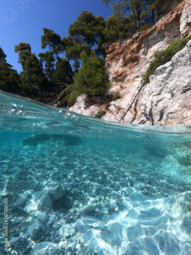 Fototapeta Naklejka Na Ścianę i Meble -  Underwater and sea level photo of amazing tropical rocky turquoise clear seascape with caves and natural pine trees