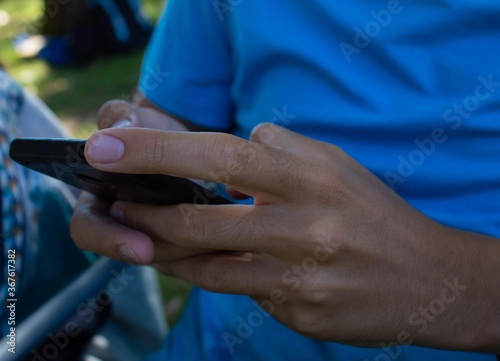 young man in blue t-shirt skillfully driving his cell phone and texting
