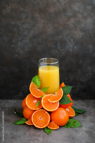 A glass of orange juice. Lots of orange slices. Minimalism. Dark gray background. photo