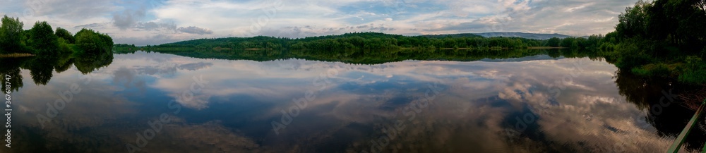 Fototapeta premium Panoramic landscape from the lake with colorful clouds in the summer sun.