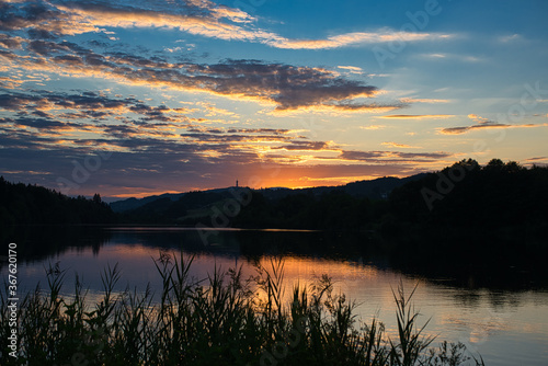 sonnenuntergang mit dramatischem wolkenhimmel spiegelnd im wasser an einem abendlichen see