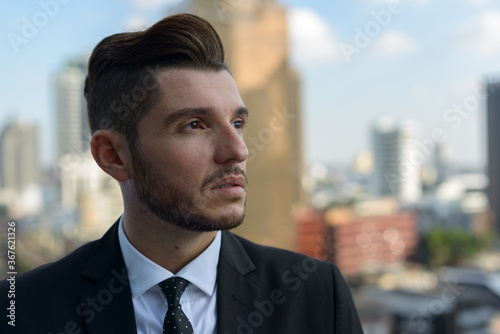 Handsome bearded Hispanic businessman against view of the city