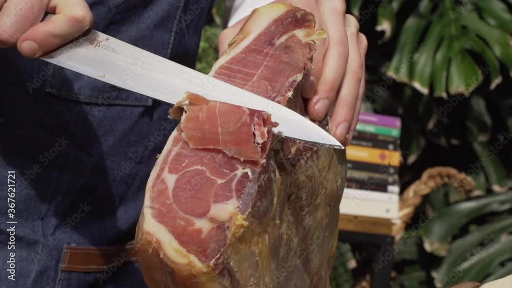 Hombre cortando jamon en una cocina al aire libre