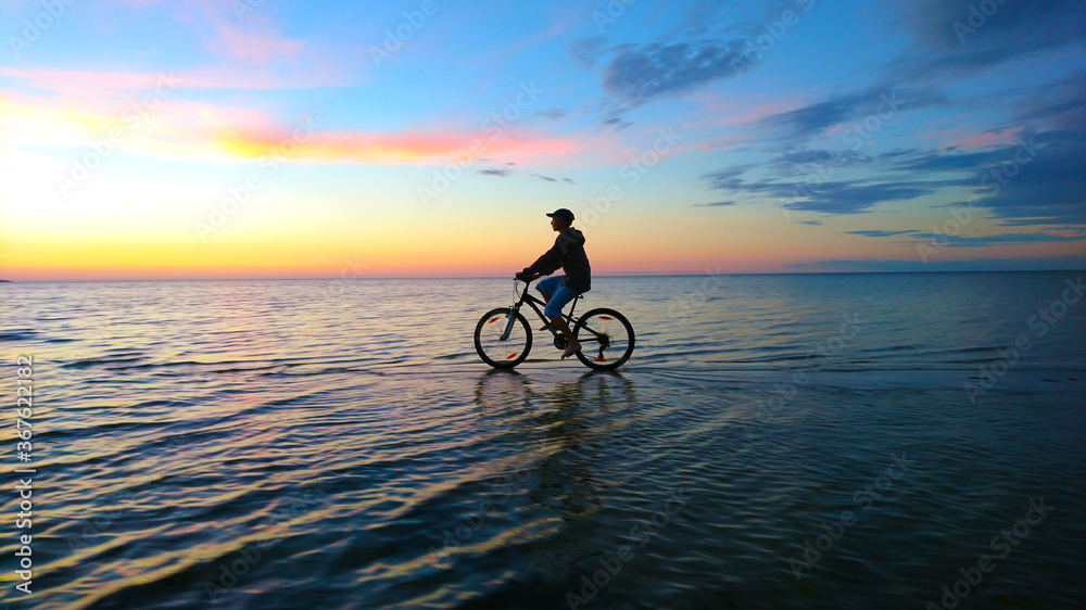 Fototapeta premium silhouette of a cyclist on the sea during sunset