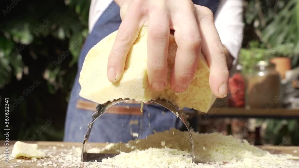 Hombre rayando queso duro en una tabla de madera 