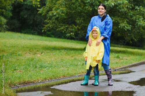 Mother and child, boy, playing in the rain, wearing boots and raincoats © Serhii