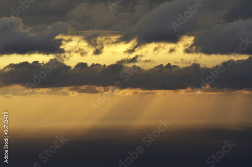 Sun rays shining through stormy clouds at sea 
