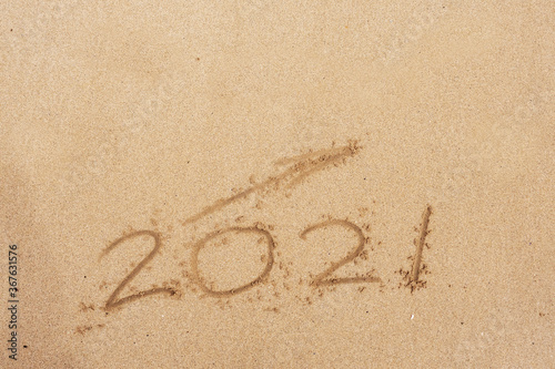 Hand written sign on a yellow warm sand 2021 and arrow going up. Positive rise in 2021 year.