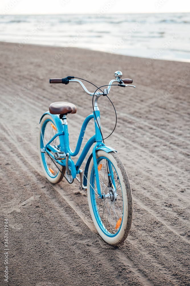 Fototapeta premium Light-blue bicycle on the beach with the sea on the background