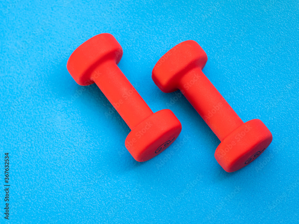 A shot of dumbbell weights on the blue background A shot of dumbbell weights on the blue background