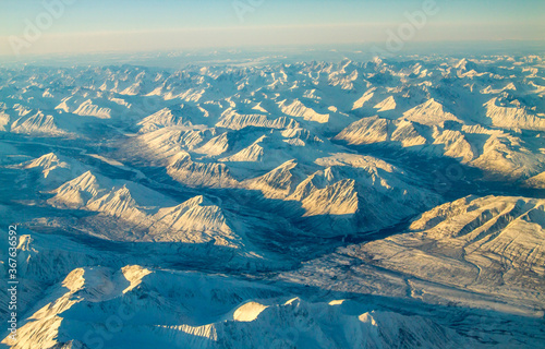 An aerial view of snow covered mountain ranges on a cold winter morning between Red Devil and Nome Alaska