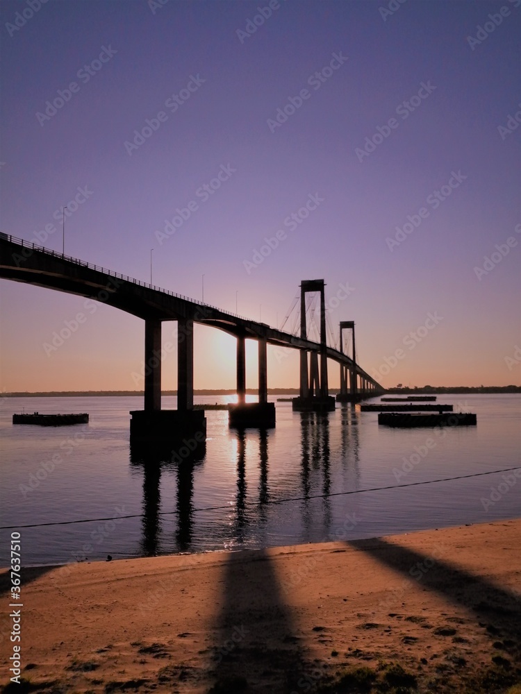 Playa, costa del río y puente al atardecer