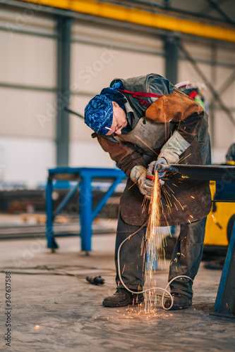 Worker Using Angle Grinder in Factory