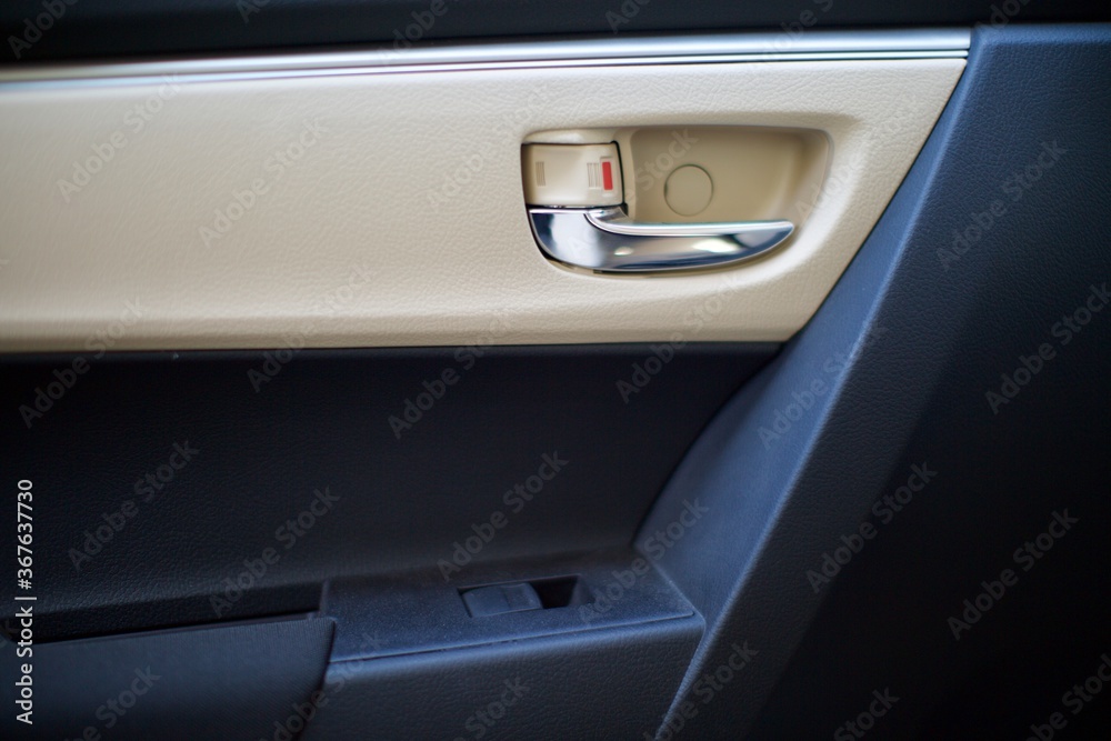 interior view of car door handle. also electronic window release button can be seen. the interior is beige and black.