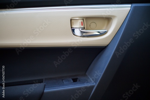 interior view of car door handle. also electronic window release button can be seen. the interior is beige and black.