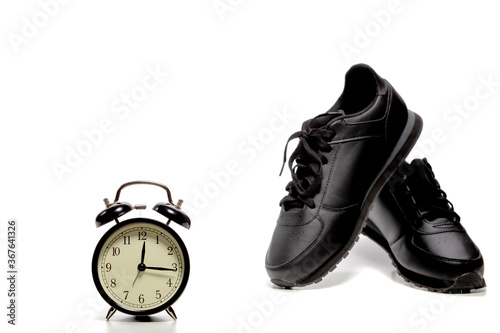 It Is Time To Run! Pair of Black Trainers Along with Clock Alarm in Foreground.