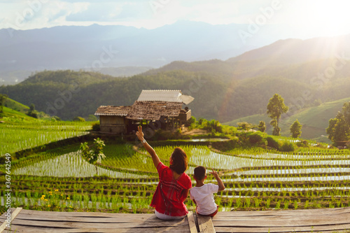 Happy time of mother with son sitting on wooden bench and enjoying Terrace rice fields at Bann Bong Piang in Mae chaem, Chaing Mai, Thailand.