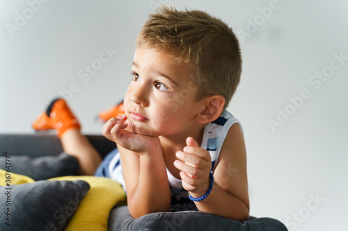 Tableau sur toile Close up portrait of small boy lying on couch or sofa bed at home - Little kid r
