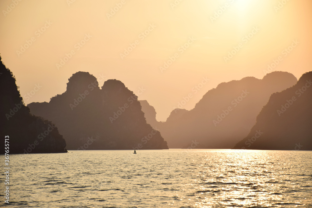 Halong Bay (UNESCO World Heritage) during a cloudless sunset with outlines of the beautiful karst landscape, Vietnam