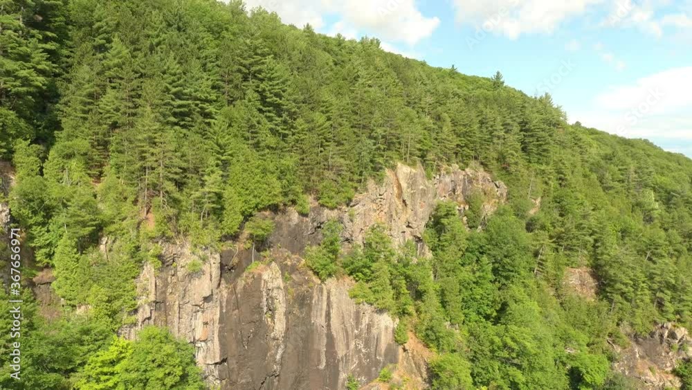 Vertical cliffs covered in pine forests in Canada on blue sky with few clouds Vertical cliffs covered in pine forests in Canada on blue sky with few clouds