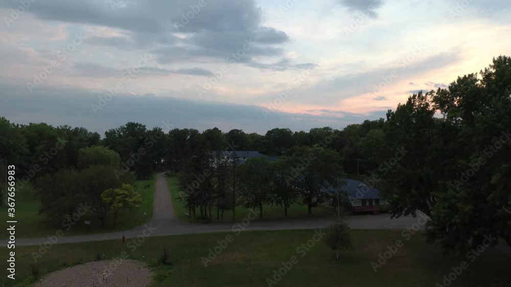 Drone lifting up over convent in wooded area near large body of water Drone lifting up over convent in wooded area near large body of water