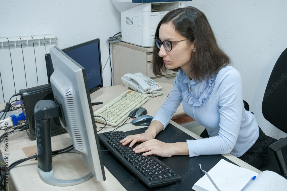 Brunette girl working at the computer in the office Brunette girl working at the computer in the office