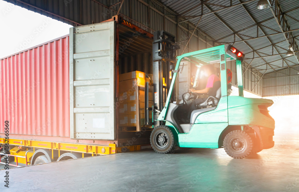 Forklift tractor loading cargo shipment pallet goods into the truck container at dock warehouse. Cargo freight industry delivery warehouse logistics transportation.