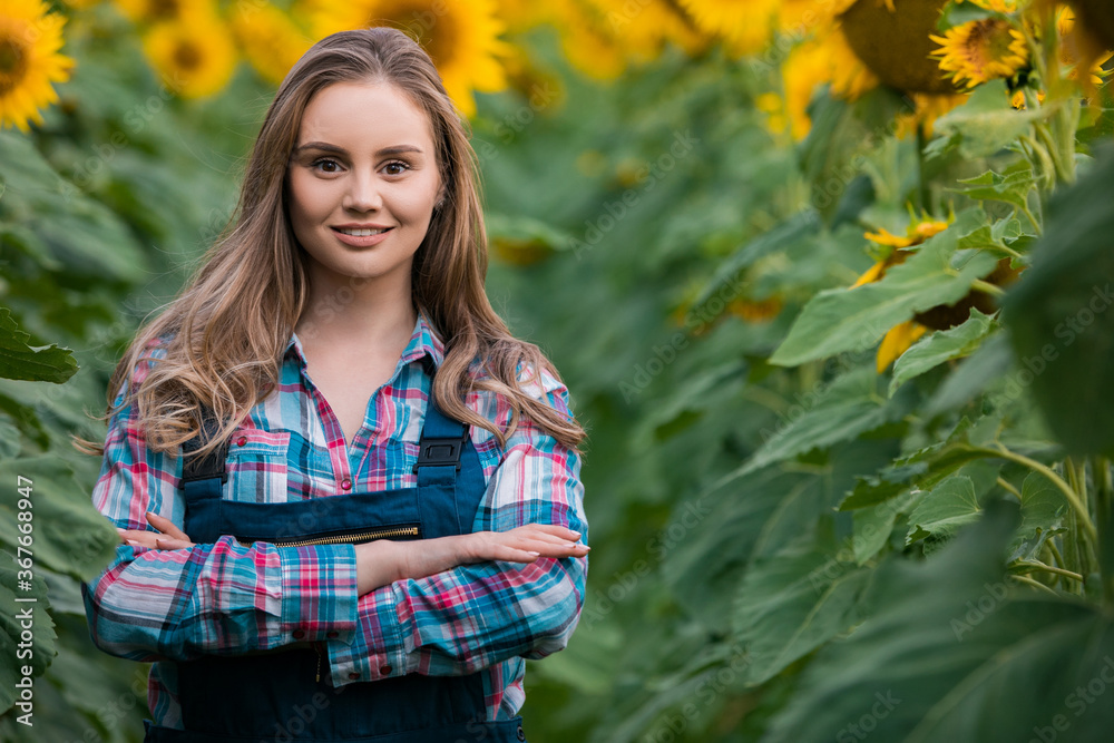Gorgeous, young, energetic, female farmer standing in the middle of a beautiful green and golden sunflower field. Gorgeous, young, energetic, female farmer standing in the middle of a beautiful green and golden sunflower field.