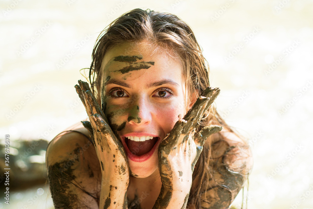 Dirty female model. Woman in clay mask laughs. Crazy girl in medical mud.  Spa Outdoor. Happy dirty woman in Dead sea. Young woman enjoy natural  mineral mud sourced from Dead sea. Photos