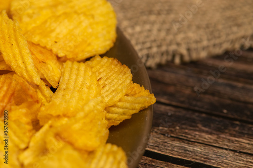Fluted potato chips on a wooden background. Close up.