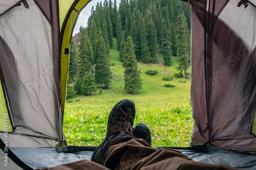Man is laying in tent in beautiful mountains. Camping in mountains. Tourism hiking concept. Adventure travel. Active lifestyle.