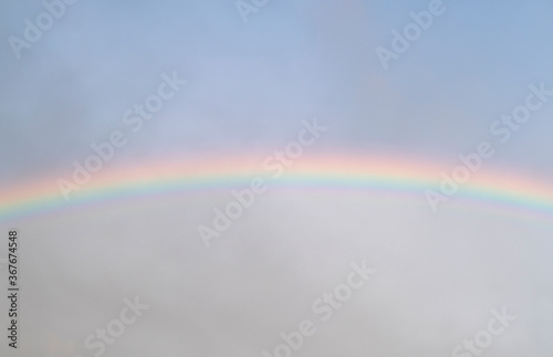 Sky rainbow. Sky rainbow over the clouds. Rainbow sky landscape. Rainbow background. Rainbow sunset. Beautiful colourful rainbow in the sky. © Aleksei