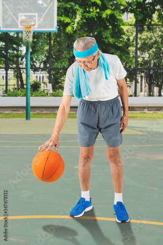 Elderly man dribbles a basketball at basketball court