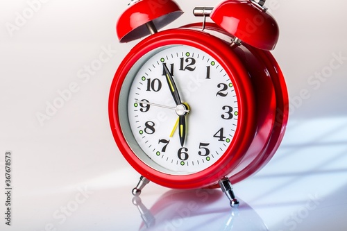 Red alarm clock close up on white glass table