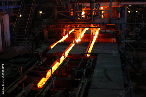 Red hot steel metal billets after molten steel casting.  Continuous casting machine. Background of the blacksmith and metallurgical industry.