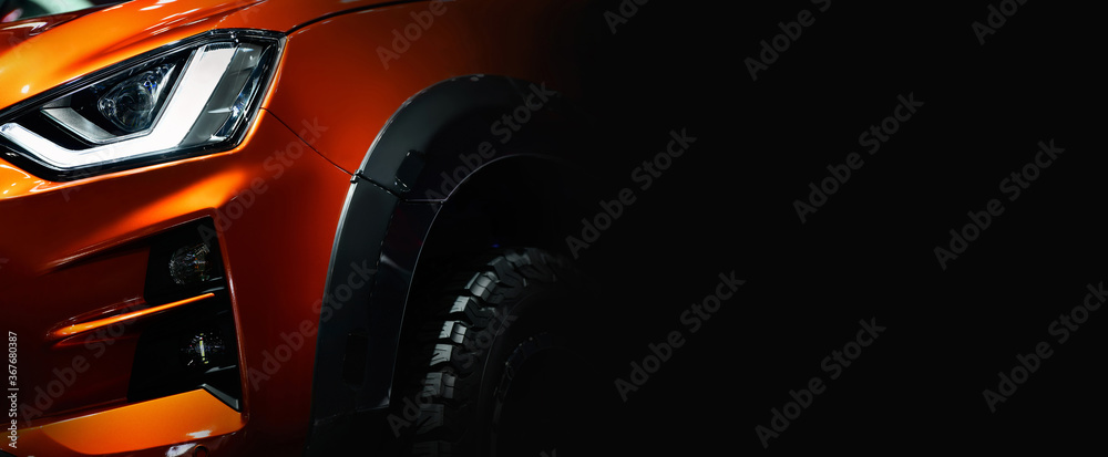 Close up detail on one of the LED headlights orange Pickup Truck on black background free space on right side for text. - obrazy, fototapety, plakaty 