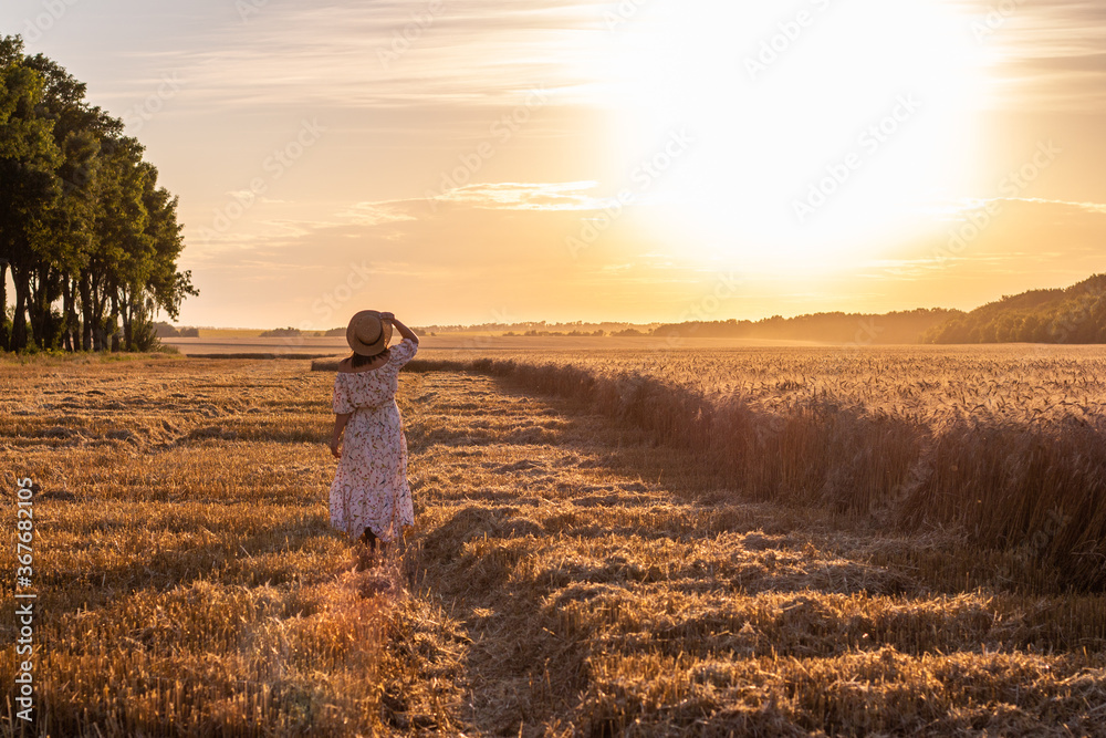 girl in the field at sunset from the back