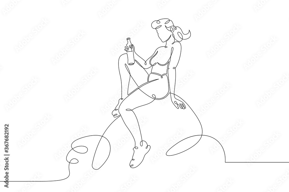 Fototapeta dziewczyna z butelką siedzi na kamieniu nad wodą morską
