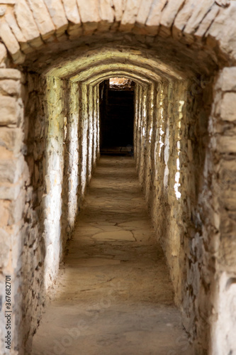Narrow passage along the wall of a medieval castle, with windows for shooting.