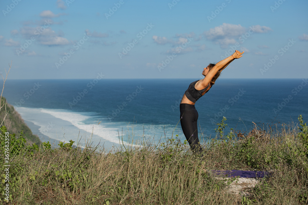 Young woman doing yoga outdoors with amazing back view. Bali. Indonesia.