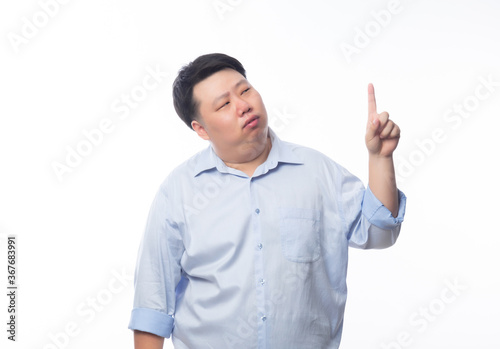 Asian Fat Man in blue shirt thinking and pointing to copyspace with doubts face isolated on white background.