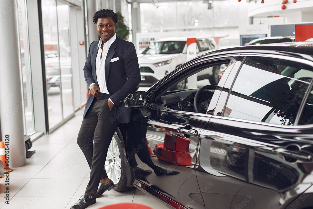 Man buying the car. Businessman in a car salon. Black male in a suit. Man buying the car. Businessman in a car salon. Black male in a suit.
